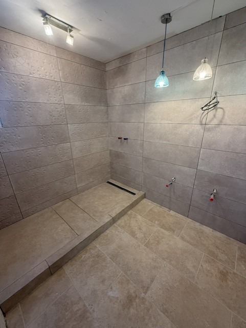 Salle de bains en cours de rénovation avec carrelage mural et receveur de douche