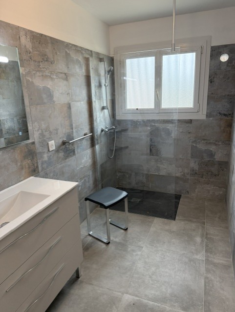 Salle de bains carrelée avec douche, paroi vitrée et meuble vasque